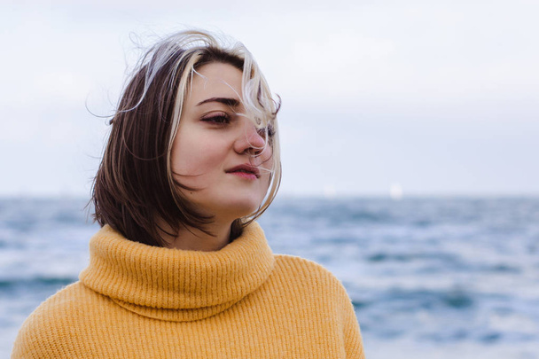 portrait of beautiful young woman in yellow pullover sweater on the beach - Фото, зображення