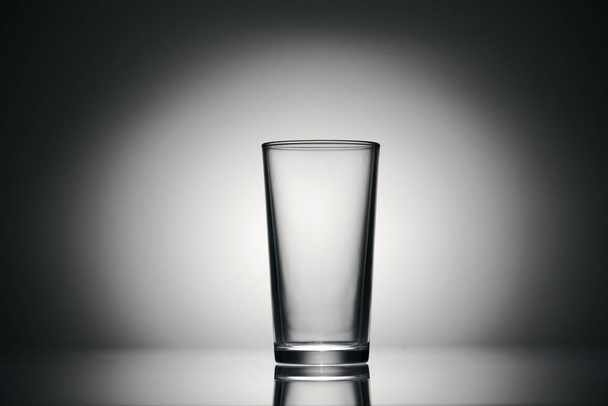 um copo vazio para água sobre um fundo escuro
 - Foto, Imagem
