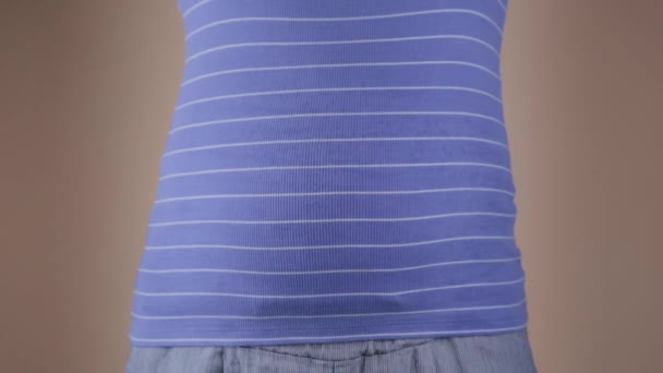 Een close-up van de buik van een zwangere vrouw in een blauw T-shirt, die in haar handen folders met de inscripties reizen en vraagteken houdt. Het concept van het vinden van een vader tijdens de zwangerschap - Video