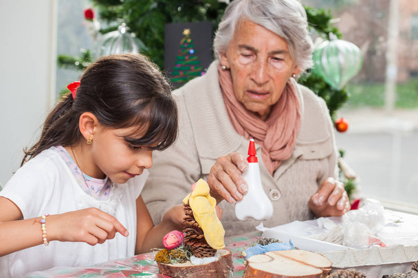 Niña divirtiéndose mientras hace artesanías navideñas de Navidad con su abuela - Familia real
 - Foto, imagen