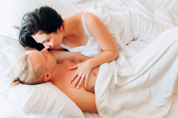 Boyfriend and his girlfriend are lying on white sheets. Morning of a young couple. Relationship. - 写真・画像
