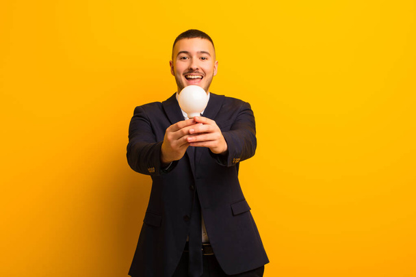 young handsome businessman  against flat background with a light bulb - Fotoğraf, Görsel