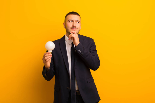 young handsome businessman  against flat background with a light bulb - Photo, Image