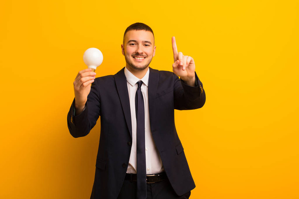 young handsome businessman  against flat background with a light bulb - Foto, afbeelding