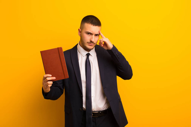 young handsome businessman  against flat background with a diary book - Fotoğraf, Görsel
