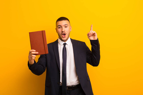 young handsome businessman  against flat background with a diary book - Foto, Imagen