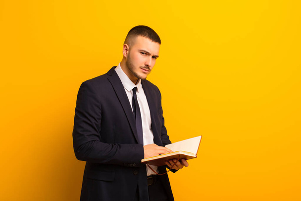 young handsome businessman  against flat background with a diary book - Photo, image