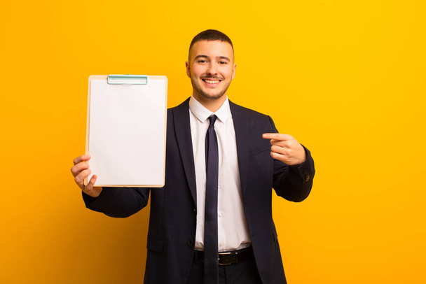 young handsome businessman  against flat background with a placard - Fotó, kép