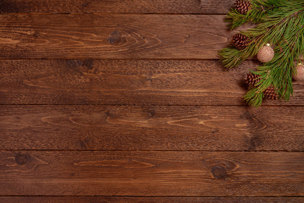Christmas or New Year decoration background. Spruce branches with cones and balls, on dark wooden  background. Flat lay, top view, copy space. - Zdjęcie, obraz