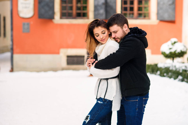 Happy couple in warm clothes hugging each other on the background of christmas tree with lights. Winter holidays, Christmas and New Year concept. - Photo, Image