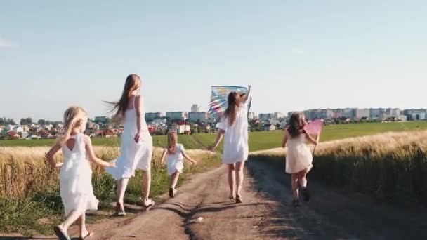 Dziewczyny w białych sukienkach na ścieżce biegnącej z siatką na motyle i latawcem - Materiał filmowy, wideo