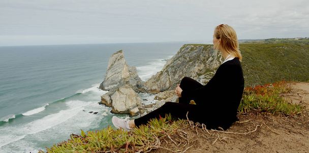 Young woman enjoys the view over the ocean at Cabo da Roca in Portugal - travel photography - Фото, изображение