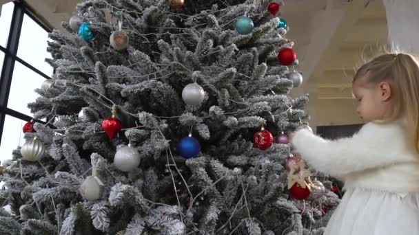 Κοριτσάκι μικρό παιδί βοηθά στη διακόσμηση χριστουγεννιάτικο δέντρο χρησιμοποιώντας παιχνίδια - Πλάνα, βίντεο