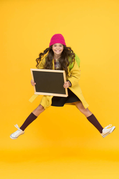 Awesome news. School schedule changes. Girl wear winter outfit blank chalkboard copy space. Fresh information. Information for children. Show information. Active jumping child excited about event - Foto, Imagem