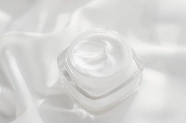Face cream moisturizer jar on silk background, moisturizing skin - 写真・画像