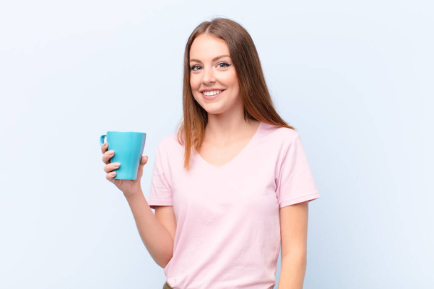 young red head woman  against flat wall with a coffee cup - Foto, Imagem