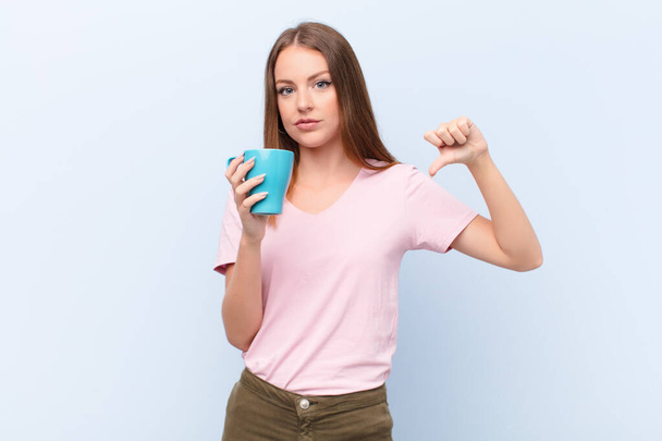 young red head woman  against flat wall with a coffee cup - Photo, Image