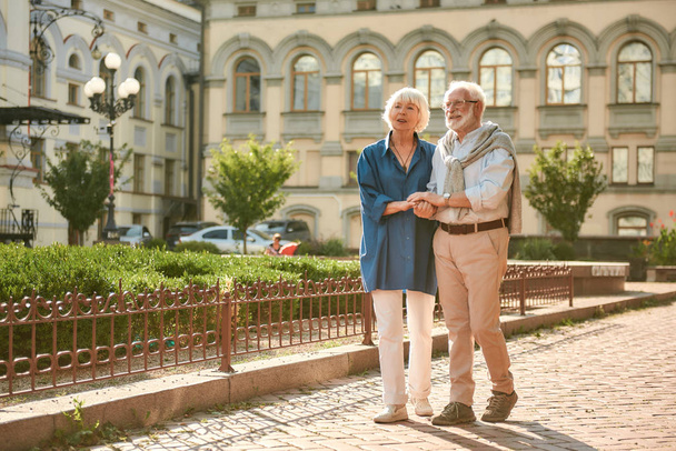 一緒に旅行する。屋外で一緒に歩いている間に幸せと美しい高齢者のカップルの手を保持 - 写真・画像