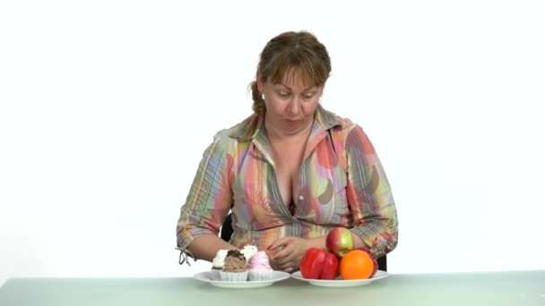 Překvapená žena si vybírá mezi zdravým a nezdravým jídlem. - Záběry, video