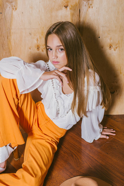 Attractive young girl with blond hair and evening make-up in retro flared pants and a chiffon boho blouse  - Foto, Imagem