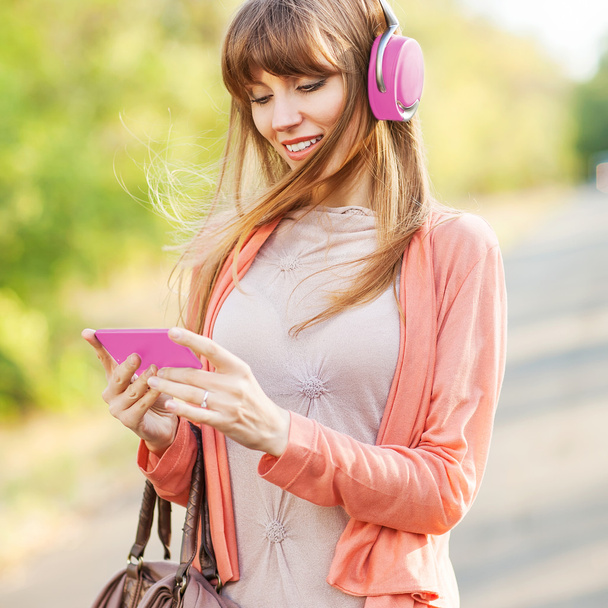 Young beautiful girl listening to MP3 player on the street - Valokuva, kuva