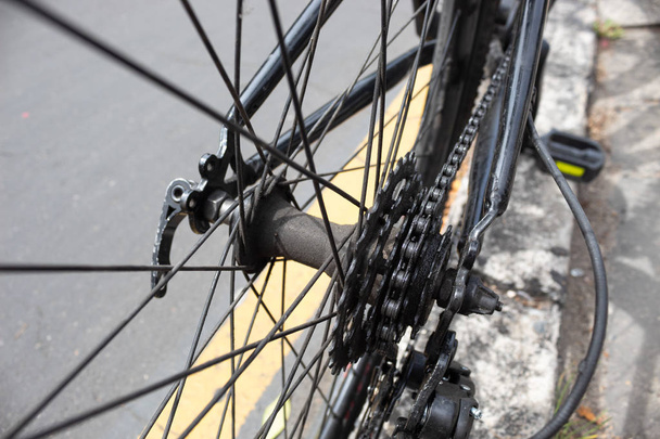verschmutzte Radnabe, Zahnräder und Speichen eines schwarzen Mountainbikes mit Asphalthintergrund - Foto, Bild