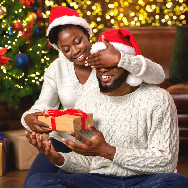 Rakastava musta nainen yllättää miehensä joululahjalla
 - Valokuva, kuva