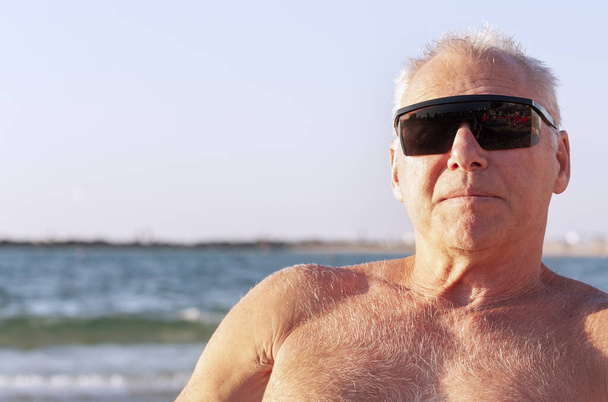 Πορτραίτο ενός ενήλικου άντρα που κάνει ηλιοθεραπεία στη θάλασσα - Φωτογραφία, εικόνα