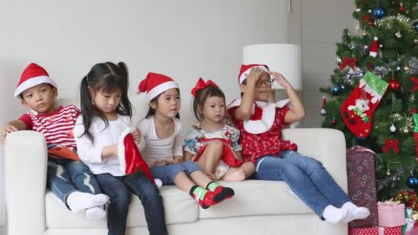 Niños pequeños con sombrero de Navidad jugando alegre en la sala de estar en el día de Navidad
. - Imágenes, Vídeo