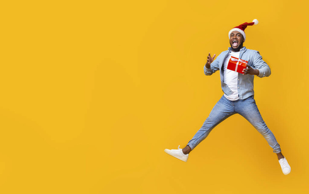 Engraçado homem negro pulando com caixa de presente de Natal
 - Foto, Imagem