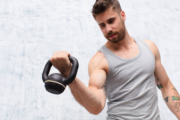 young handosme man  against flat color wall with a dumbbell sport concept - Φωτογραφία, εικόνα