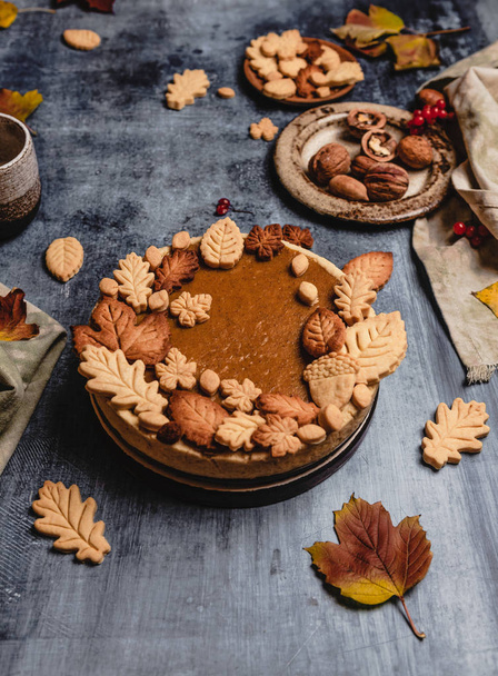 traditional pumpkin pie decorated with leaves shaped cookies on shabby blue background with textile, thanksgiving day concept - Zdjęcie, obraz
