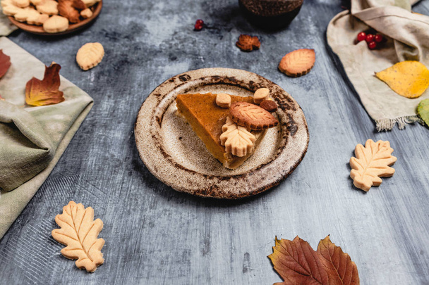 tradycyjne ciasto dyniowe ozdobione liśćmi w kształcie ciasteczek na nisko niebieskim tle z tekstyliów, koncepcja Święto Dziękczynienia - Zdjęcie, obraz