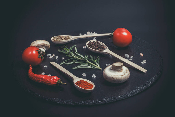 Fresh vegetables, tomatoes and mushrooms with different spices on a black background - Foto, Imagem