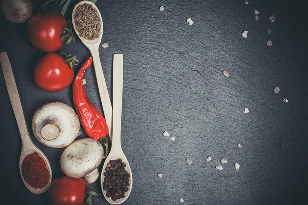 Fresh vegetables, tomatoes and mushrooms with different spices on a black background - Fotó, kép
