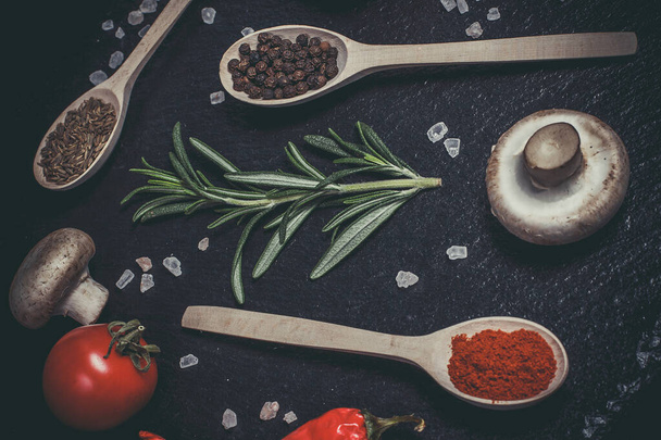 Fresh vegetables, tomatoes and mushrooms with different spices on a black background - Fotografie, Obrázek