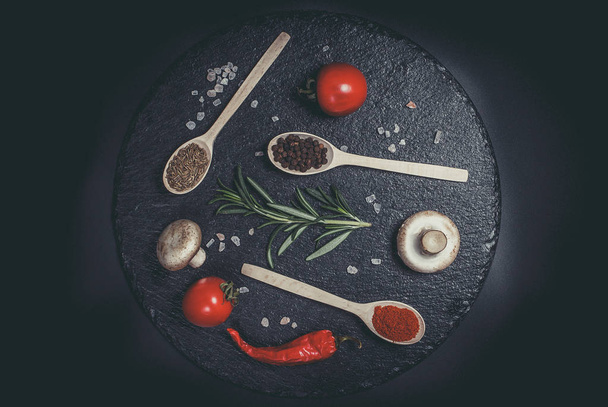 Fresh vegetables, tomatoes and mushrooms with different spices on a black background - Fotoğraf, Görsel