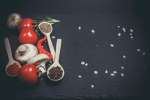 Fresh vegetables, tomatoes and mushrooms with different spices on a black background - Zdjęcie, obraz