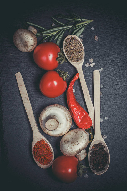 Fresh vegetables, tomatoes and mushrooms with different spices on a black background - Zdjęcie, obraz