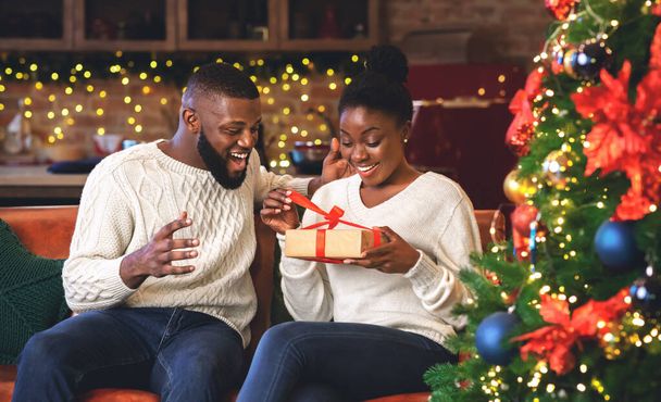 Happy zaskoczony czarny kobieta rozpakowywanie świąteczny prezent od jej chłopaka - Zdjęcie, obraz