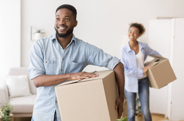 Les conjoints afro-américains portant des boîtes de déménagement entrant dans une nouvelle maison
 - Photo, image