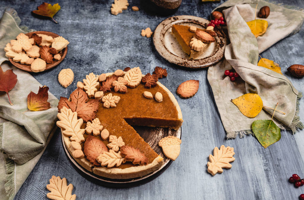 tarte à la citrouille traditionnelle décorée de biscuits en forme de feuilles sur fond bleu laiteux avec textile, concept de jour d'action de grâce
 - Photo, image