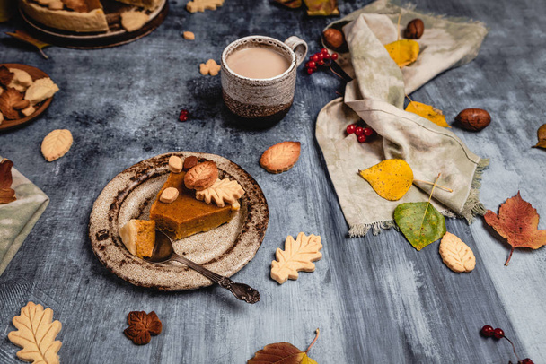 traditional pumpkin pie decorated with leaves shaped cookies on shabby blue background with coffee and textile, thanksgiving day concept - Foto, immagini