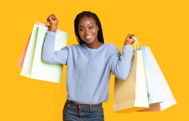 Happy black girl raising hands up with purchases - Foto, immagini