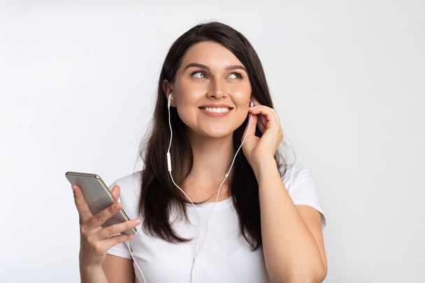 Woman In Earphones Listening Music On Smartphone Standing, Studio Shot - Фото, зображення