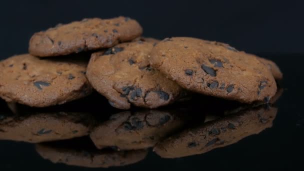 Μπισκότα σοκολάτας σε κομψό μαύρο φόντο και επιφάνεια καθρέφτη - Πλάνα, βίντεο