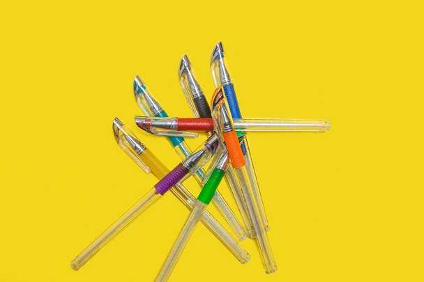 pile of colored pens lying on a yellow background - Foto, afbeelding