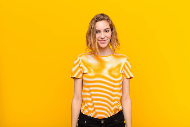young blonde woman smiling positively and confidently, looking satisfied, friendly and happy against flat color wall - Φωτογραφία, εικόνα