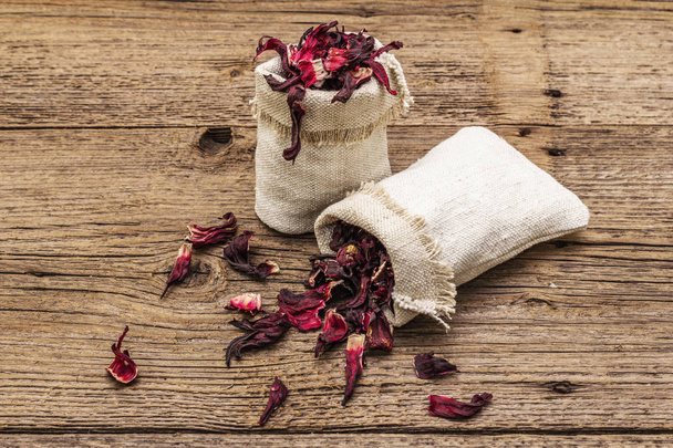 Hot hibiscus tea. Dry petals, linen sacks. Healthy food and self-care concept. Old wooden boards backgrounds - Fotoğraf, Görsel
