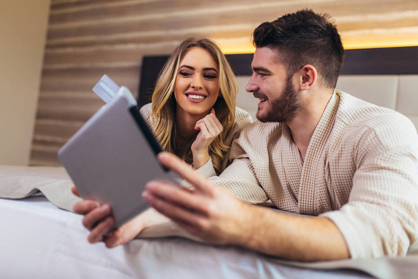 Happy couple using digital tablet while lying together in bed in - Photo, Image